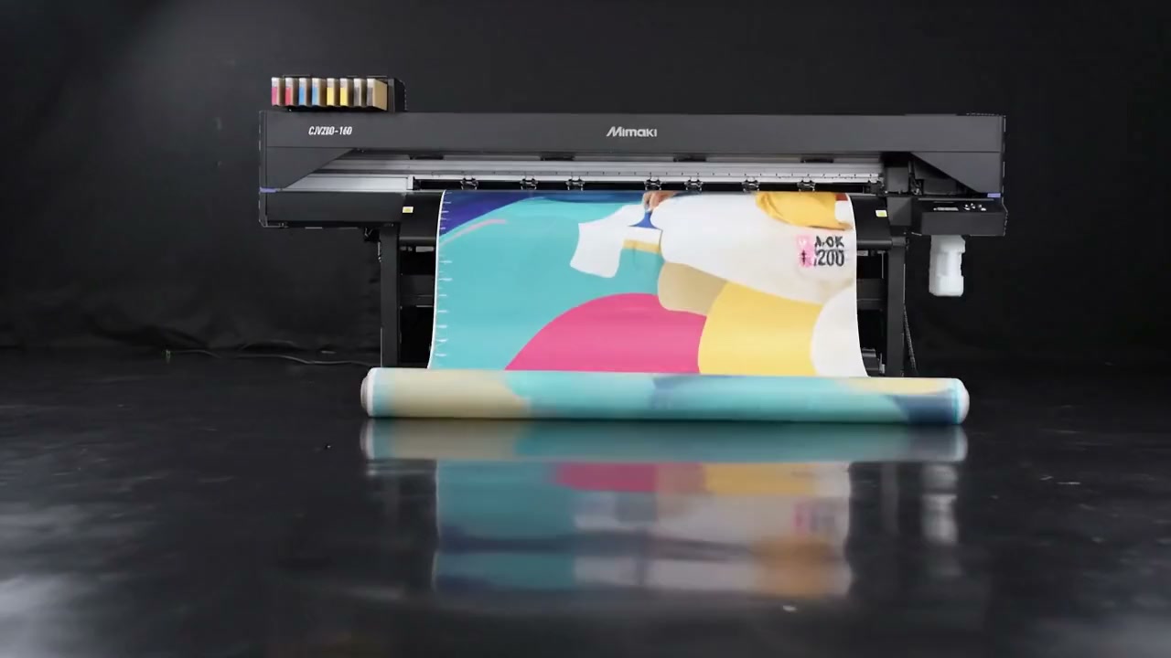 Impressora de grande formato Mimaki CJV200-160 a imprimir um rolo de vinil com formas em ciano, magenta e amarelo, em estúdio escuro.