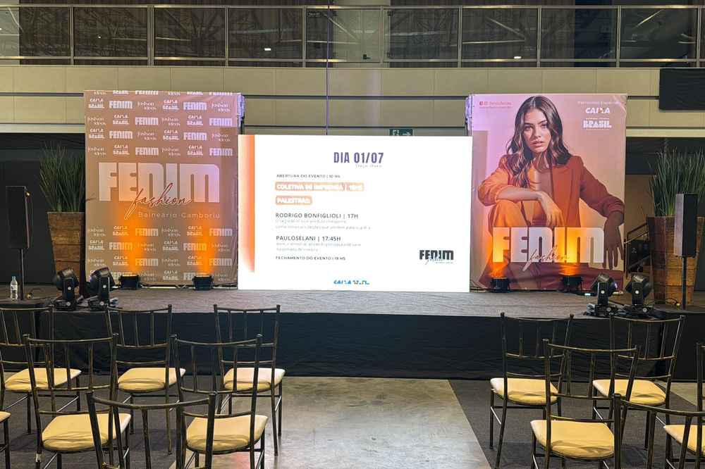 Palco de evento com fundo de cena em três painéis impressos e luzes no chão